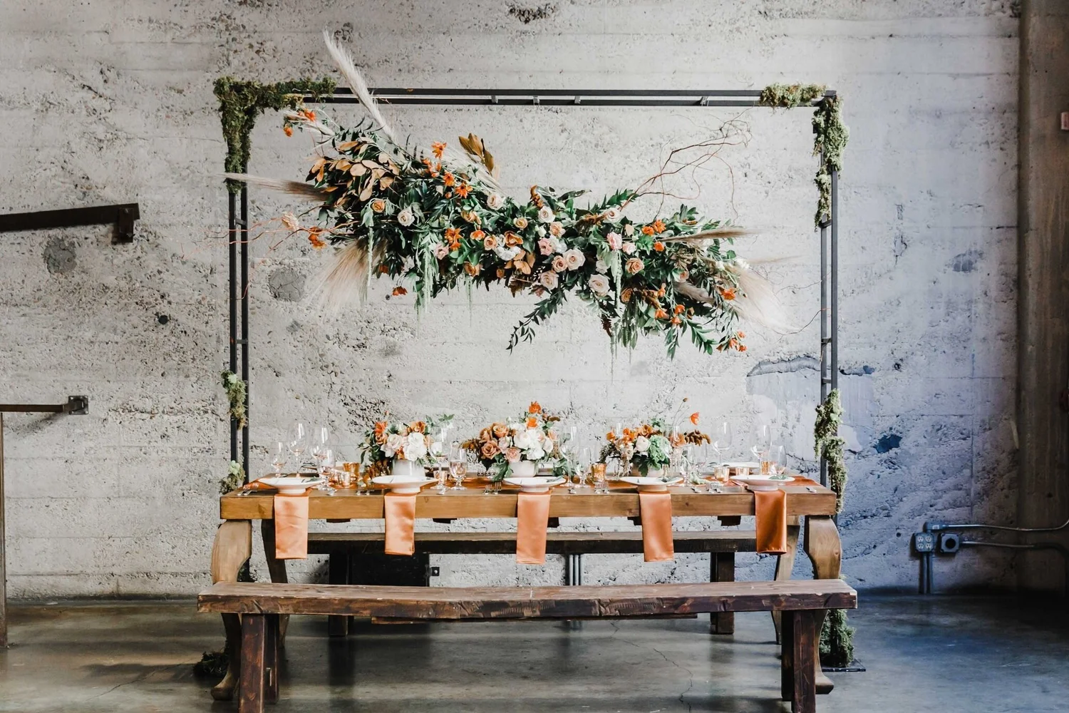 A wedding reception designed by Allen’s, with peach roses, greenery, and a suspended floral installation above the table.